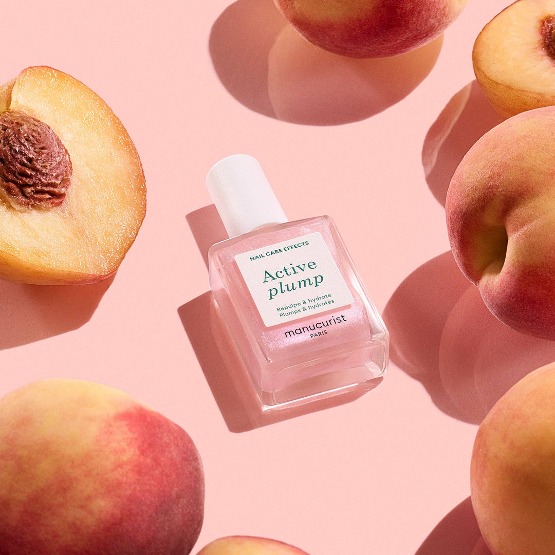 Manucurist Active Plump nail care product surrounded by peaches on a pink background