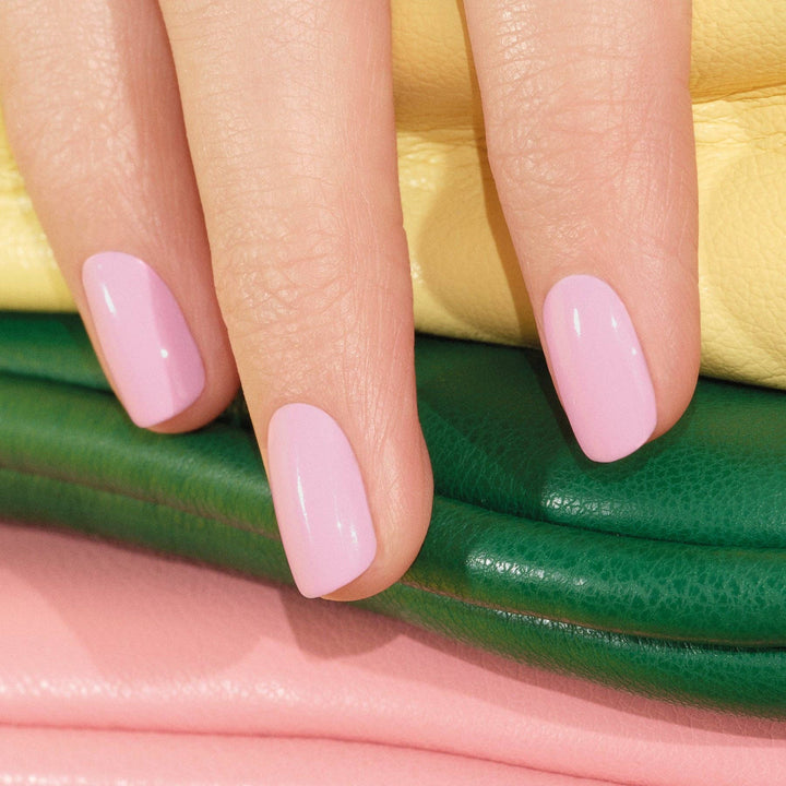 Close-up of a hand with pink nail polish on a colorful background