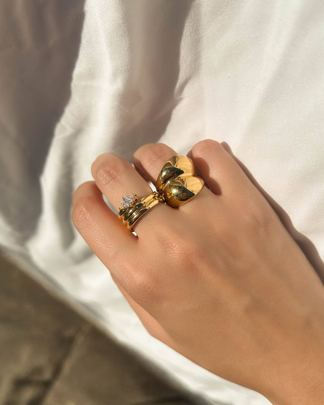 Hand wearing multiple gold rings with a blurred background