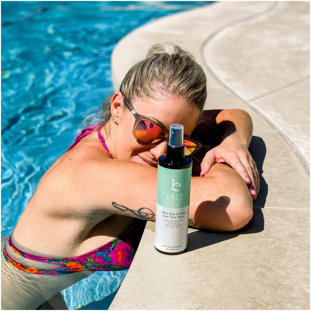 Woman in swimsuit with sunglasses and a bottle of after-sun product by a pool