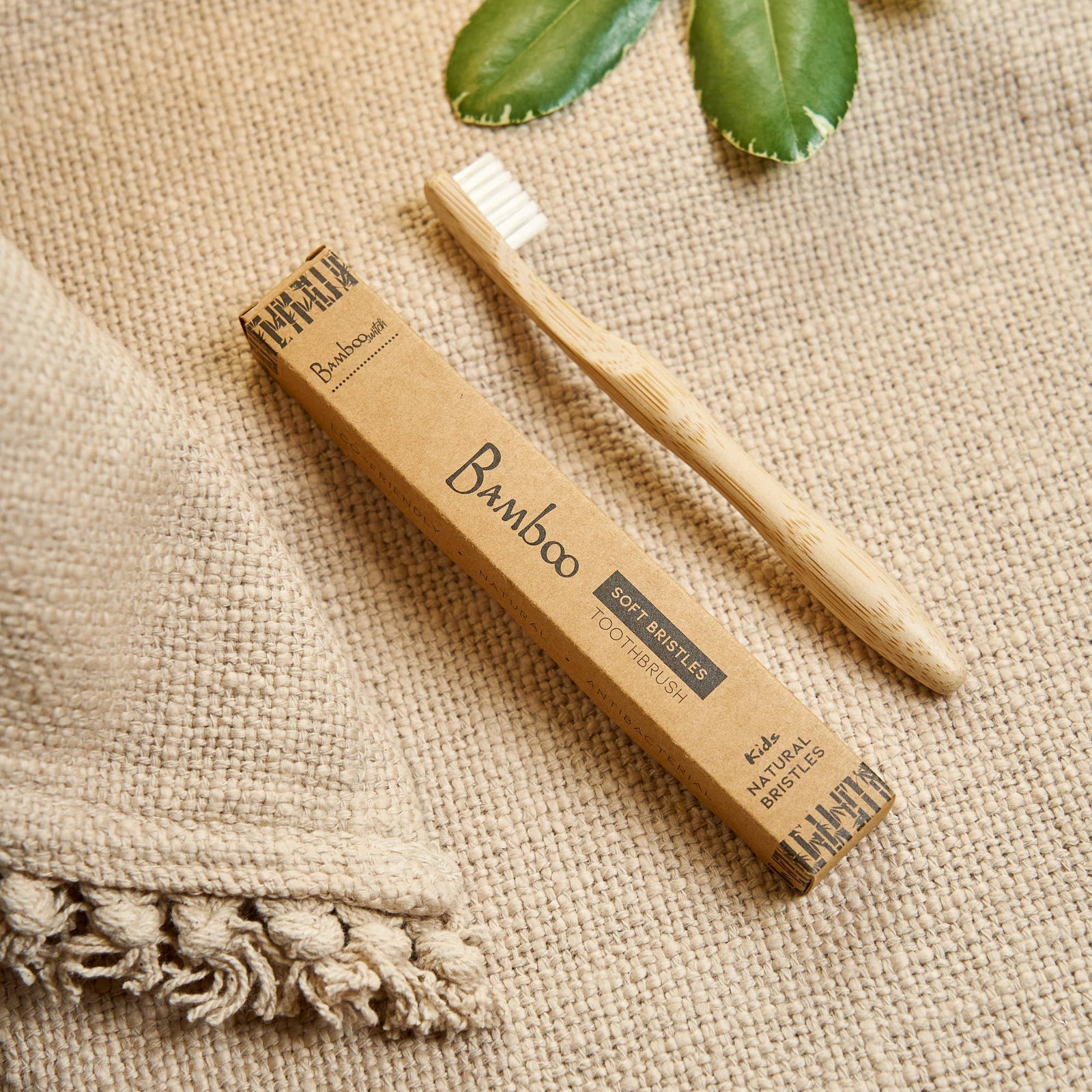 Bamboo toothbrush and packaging on a textured fabric background