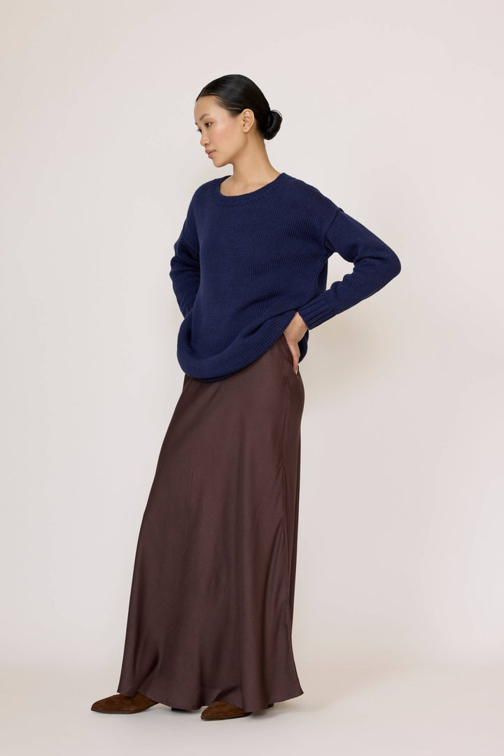 Woman wearing a Navy top and Bias Maxi Skirt in Chocolate Brown on a white background