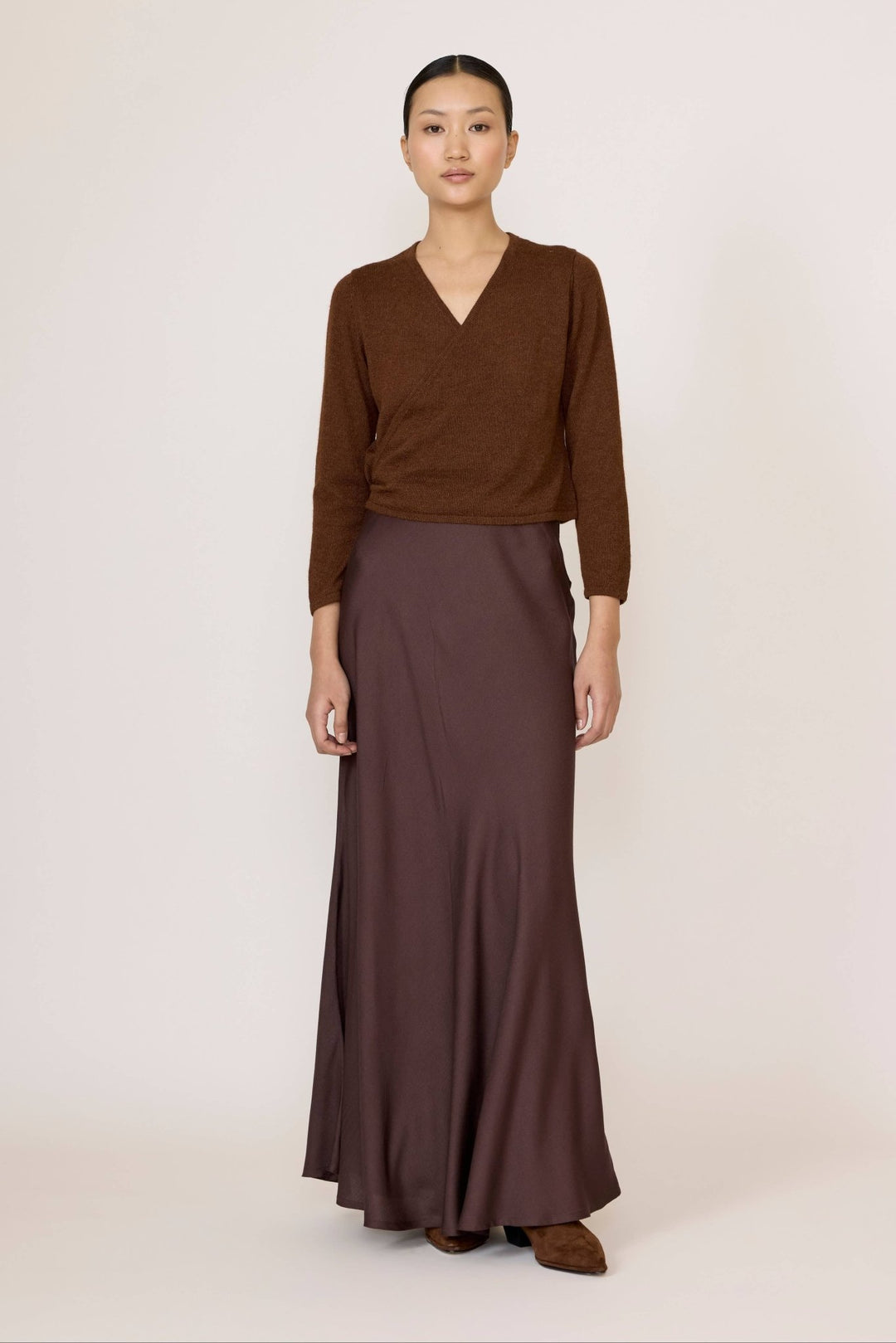 Woman wearing a brown top and Bias Maxi Skirt in Chocolate Brown on a white background