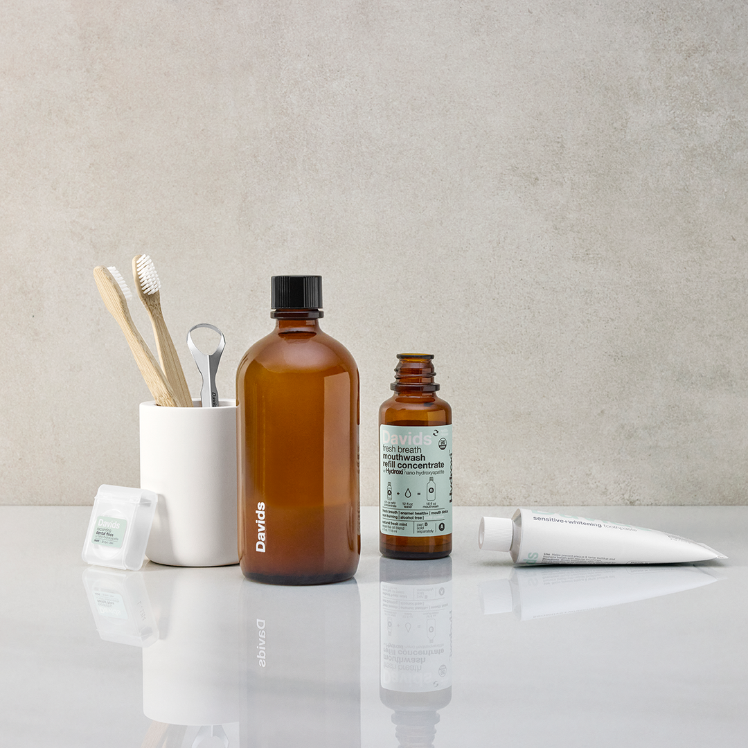 Davids mouthwash on a counter with toothpaste, toothbrush and floss.