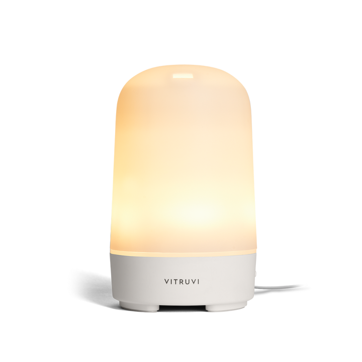 Vitruvi diffuser with light on with a gradient design on a white background