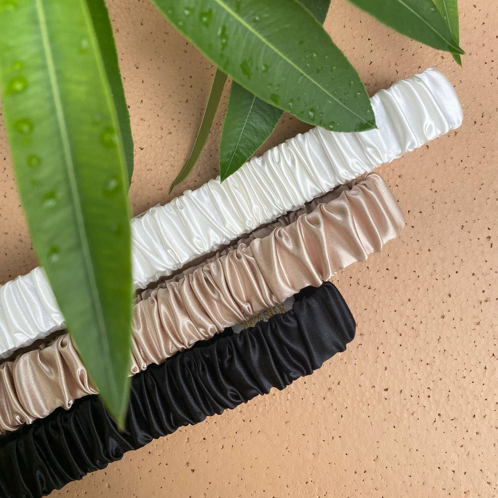 White, champagne and black silk headbands on a beige background with leafs. 