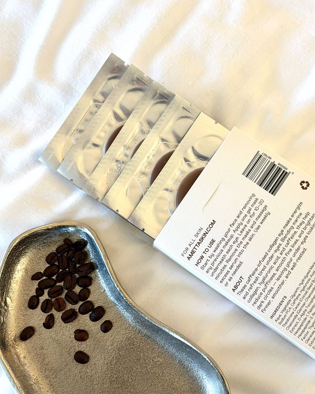 Back of Ametta eye patch box next to coffee beans on a white surface