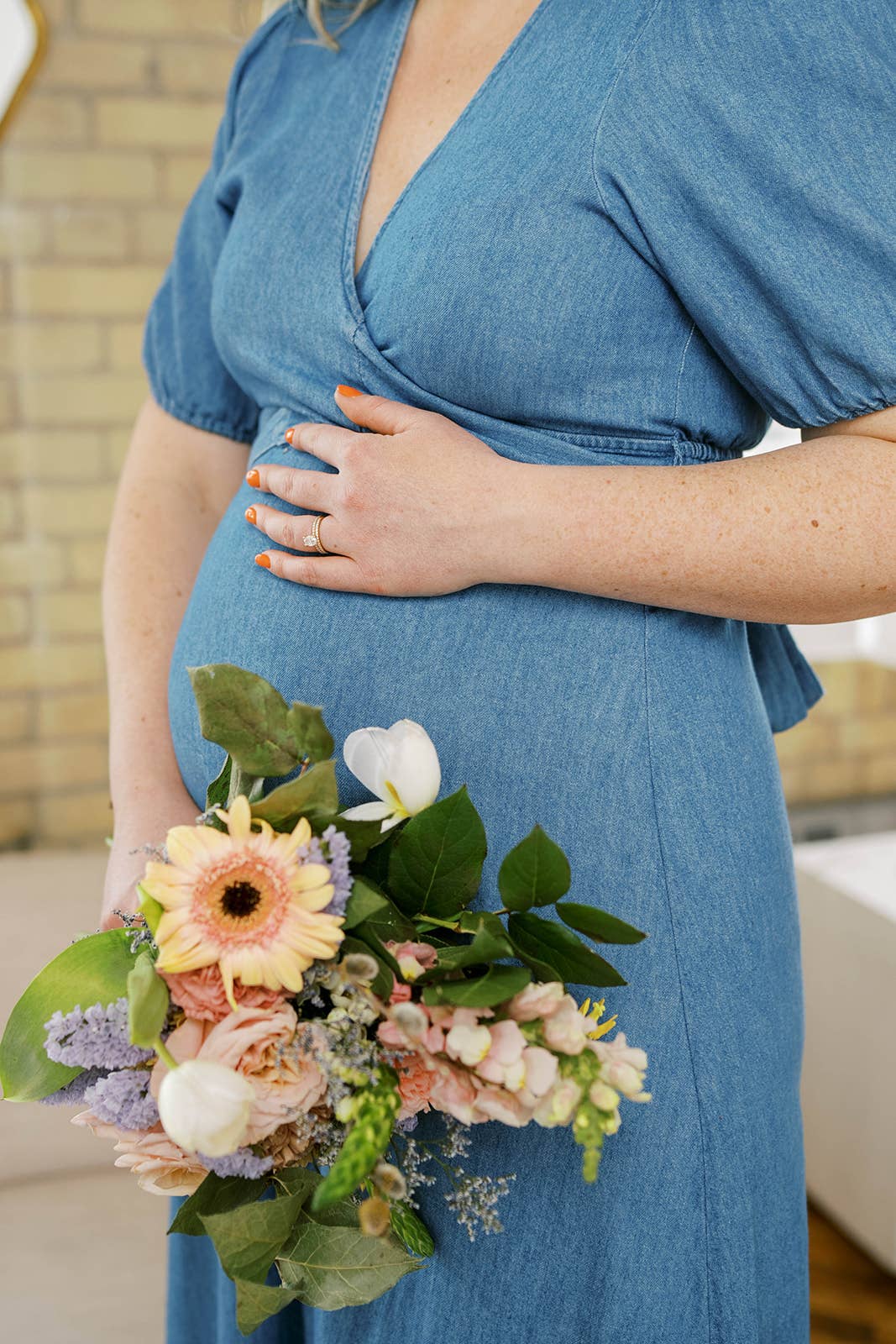 Person in a blue dress holding a bouquet of flowers indoors.