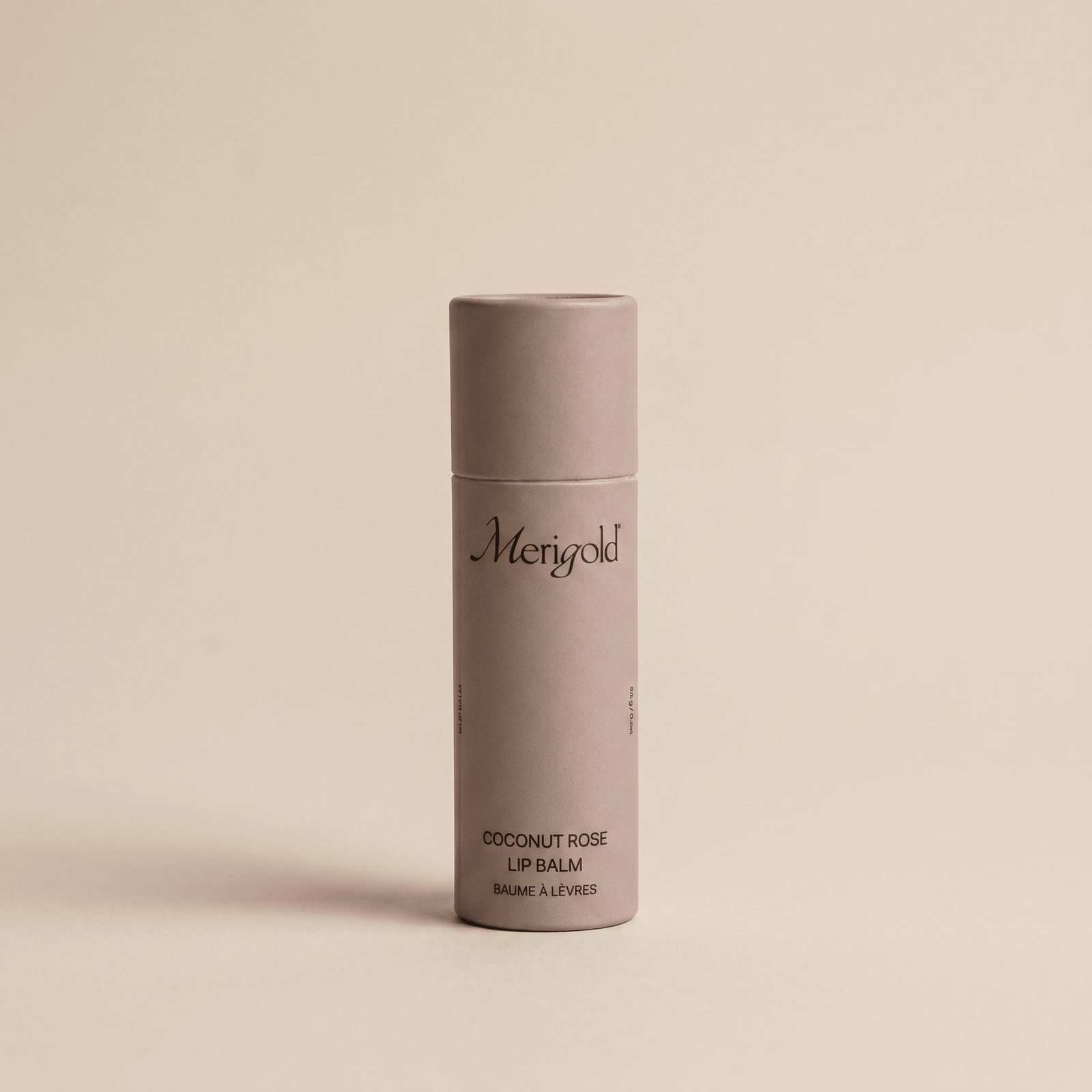Lip balm container with 'Merigold' branding on a beige background