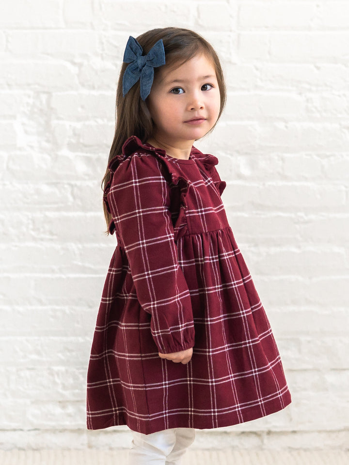 A young girl with a blue bow in her hair is wearing a Colored Organics&