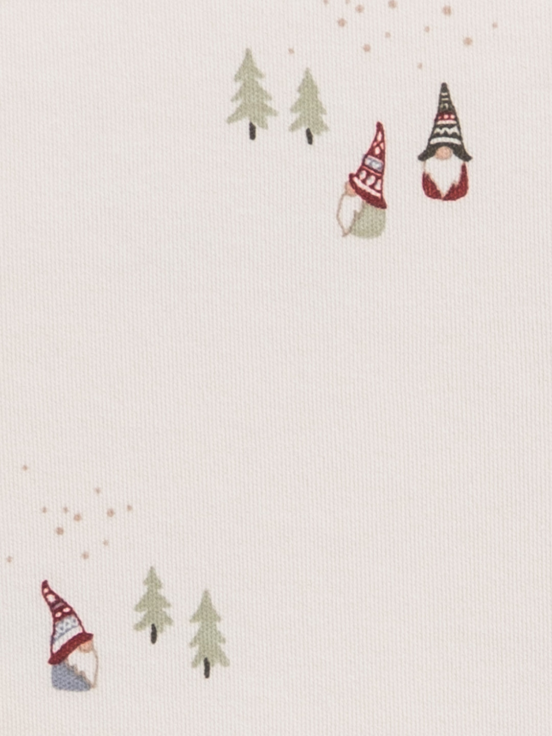 A close-up of a light cream fabric with a delicate printed pattern of small Christmas gnomes wearing red and black hats, green pine trees, and tiny gold speckles.
