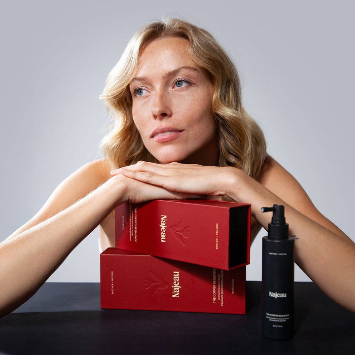 Woman with red boxes and a black bottle on a gray background