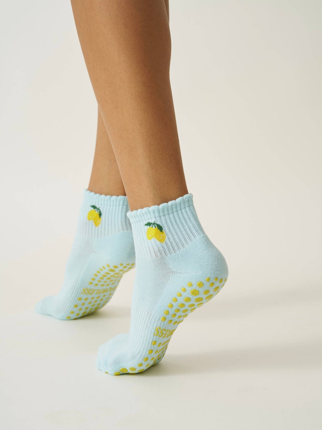 Light blue pilates socks with yellow slip-resistant dots and lemon designs on a neutral background