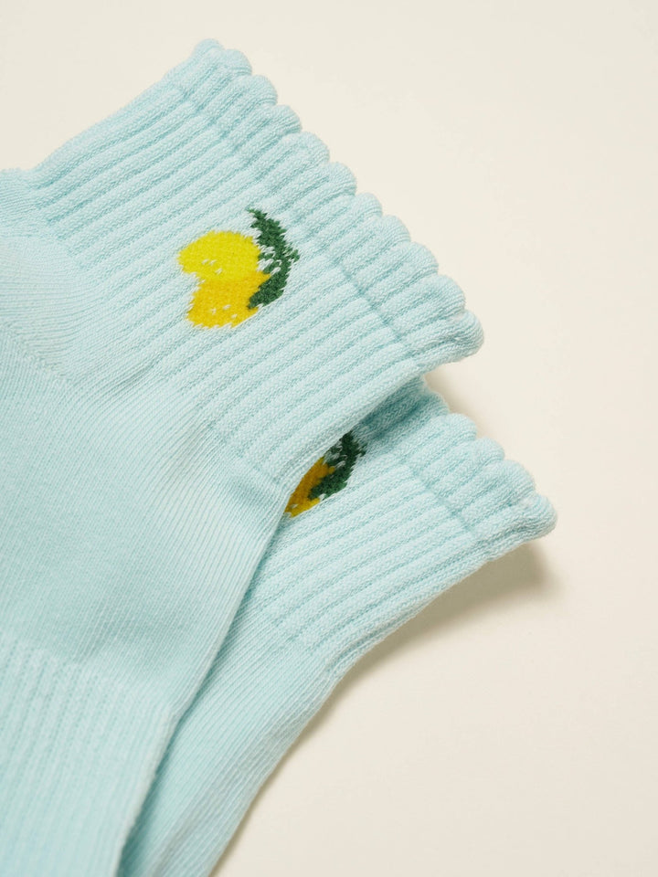 Light blue ribbed knit socks with lemon designs on a beige background