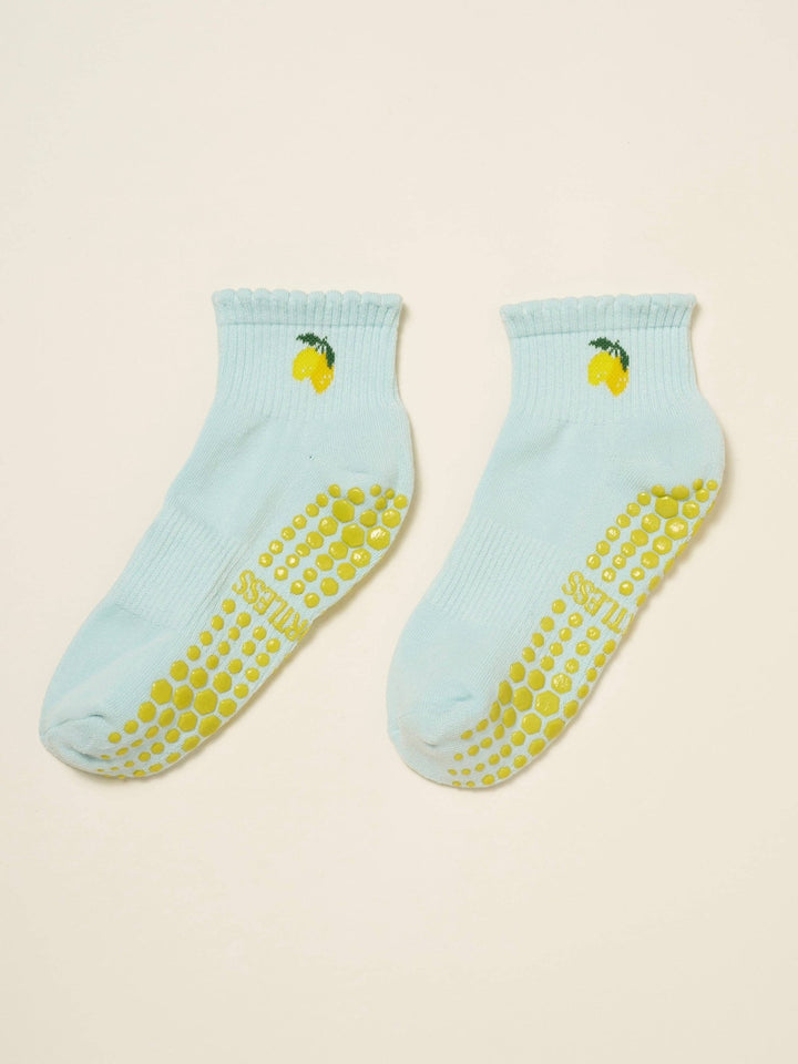 Light blue pilates socks with yellow slip-resistant dots and lemon designs on a beige background