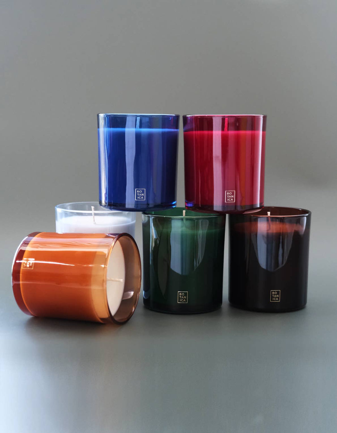 Five colorful candles stacked on a gray surface with a light gray background