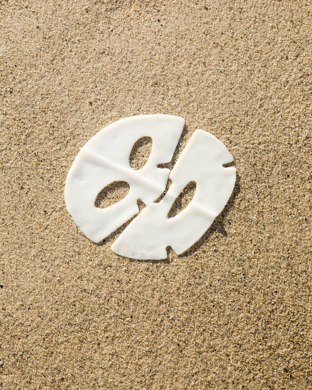 White face mask on sand background