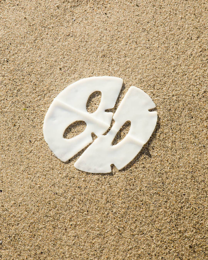 White face mask on sand background