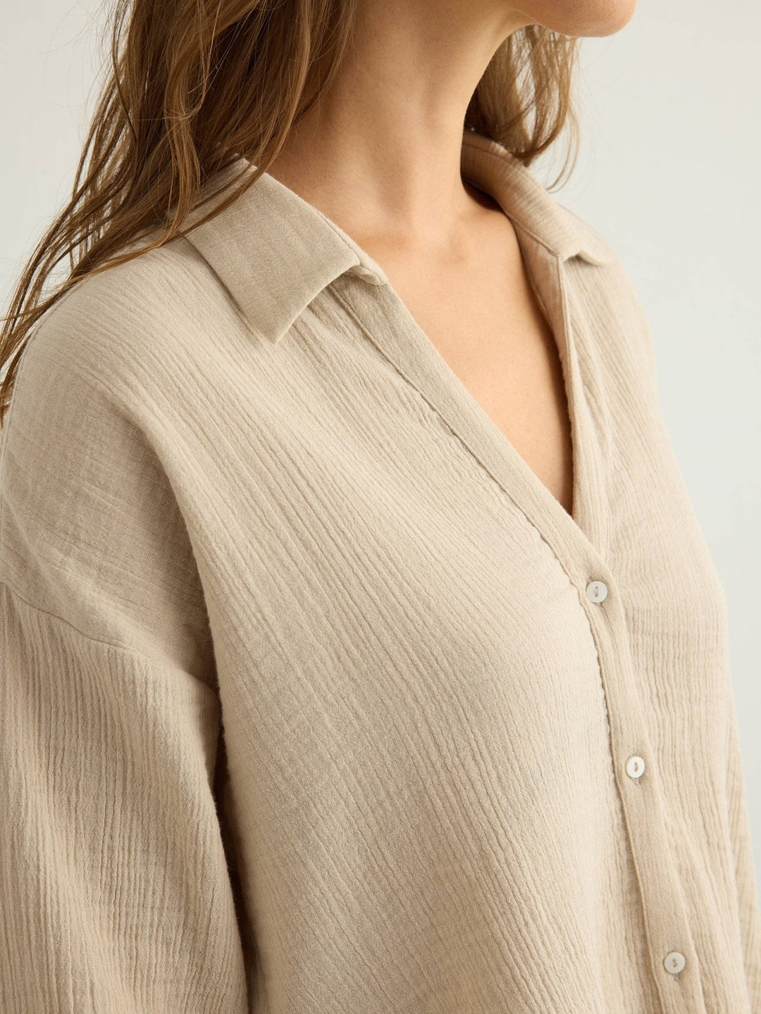 Close-up of a person wearing a Handloom oatmeal aura button-up shirt against a neutral background