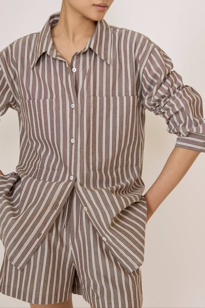 Woman wearing a Laude Everything Shirt in Acorn Stripe and matching shorts set on a plain background