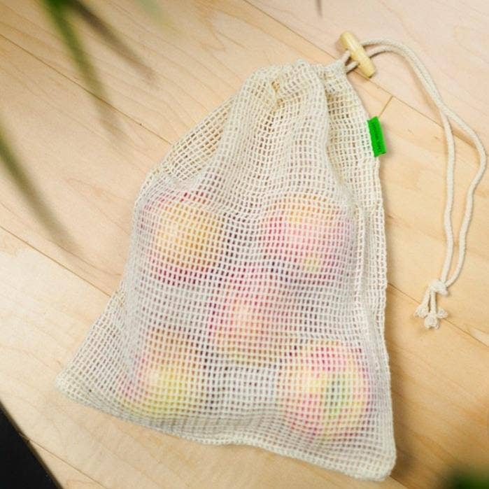 Mesh produce bag with apples on a wooden surface