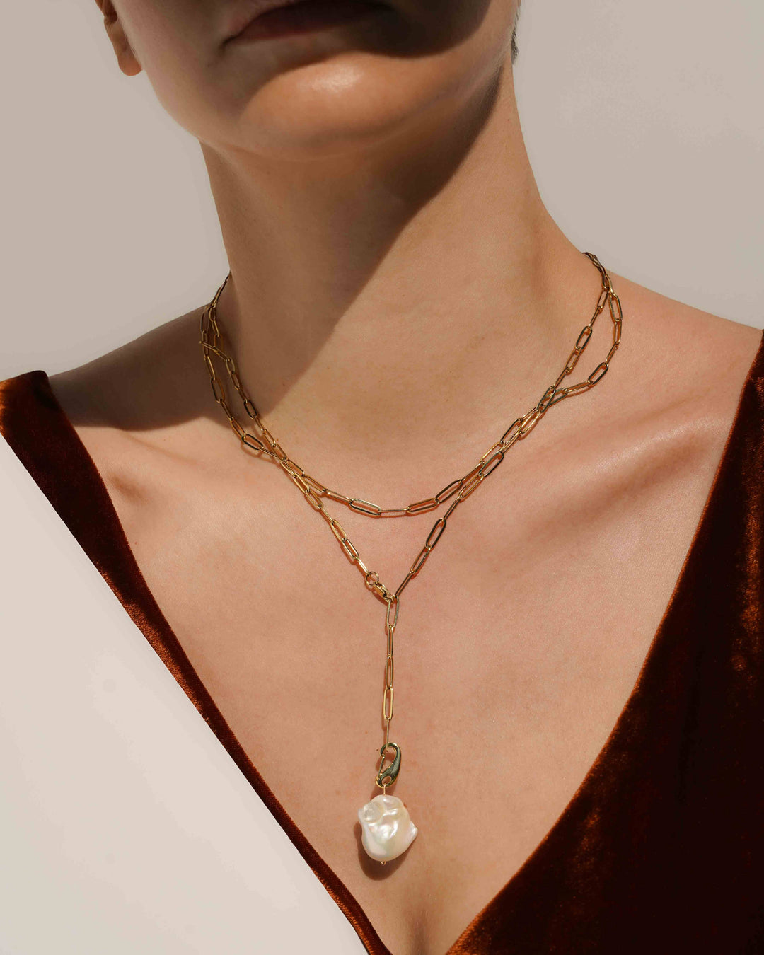 Gold chain necklace with a pearl pendant on a neutral background
