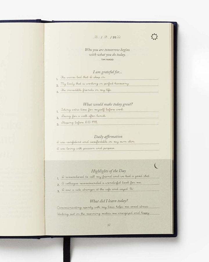 Open journal with daily reflection prompts on a white background