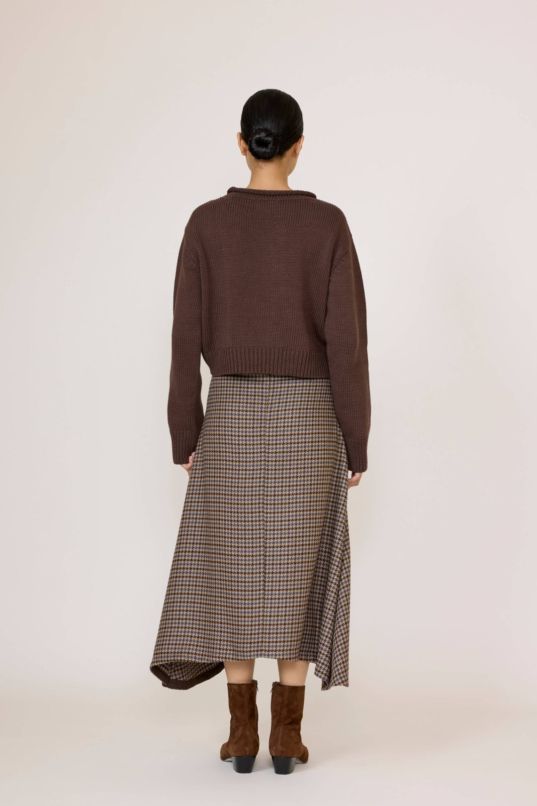 Woman wearing a brown sweater and Laude Flowy Midi Skirt in Wool Plaid on a white background