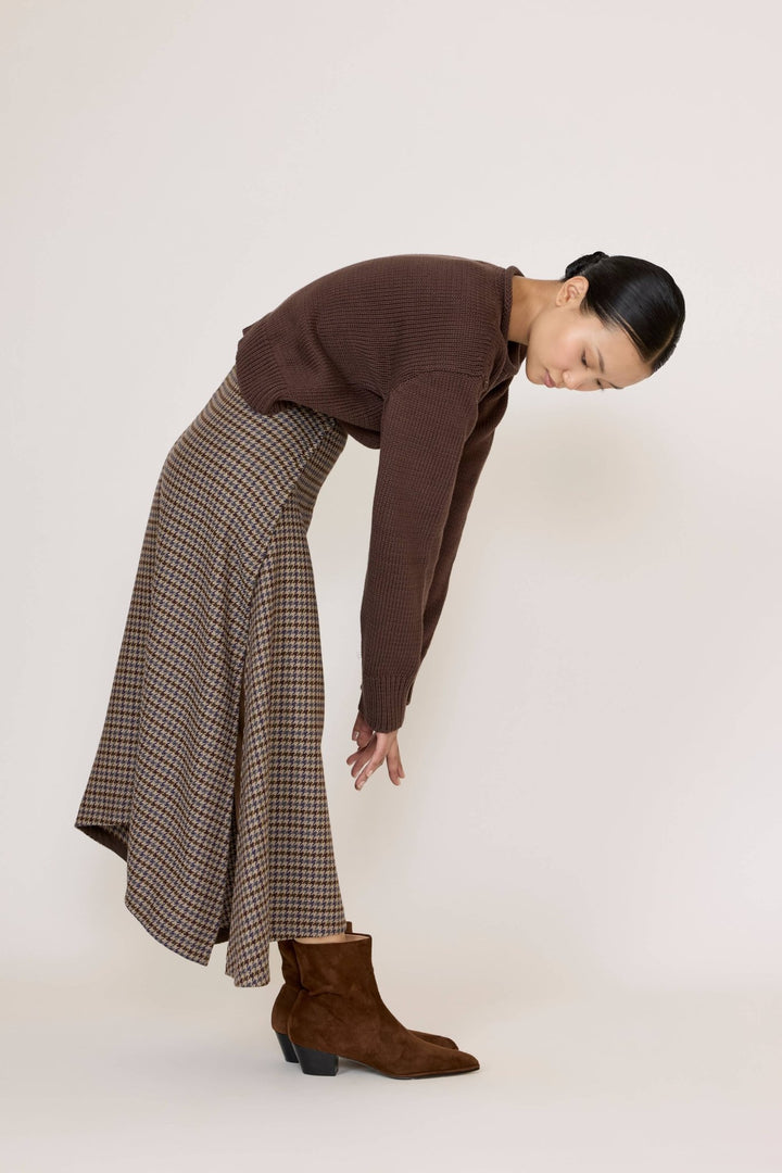 Woman wearing a brown sweater and Laude Flowy Midi Skirt in Wool Plaid on a white background