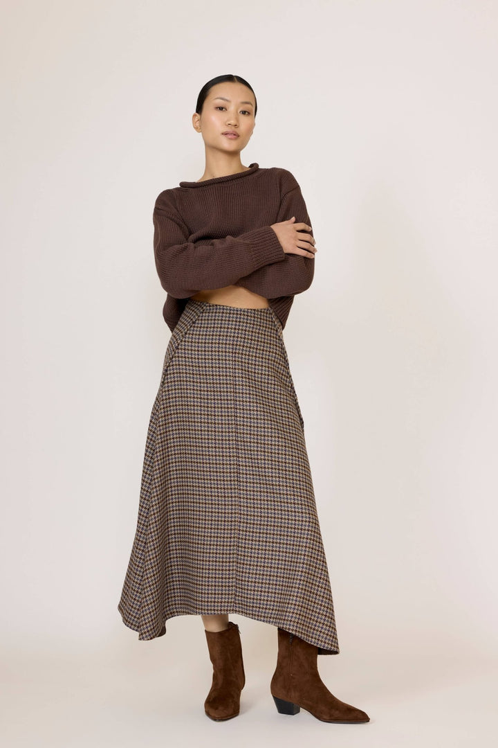 Woman wearing a brown sweater and Laude Flowy Midi Skirt in Wool Plaid on a white background