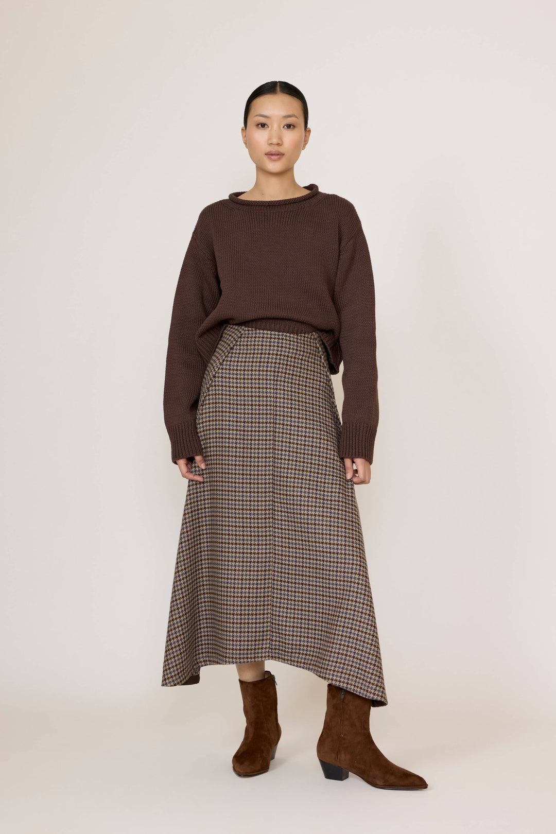 Woman wearing a brown sweater and Laude Flowy Midi Skirt in Wool Plaid on a white background
