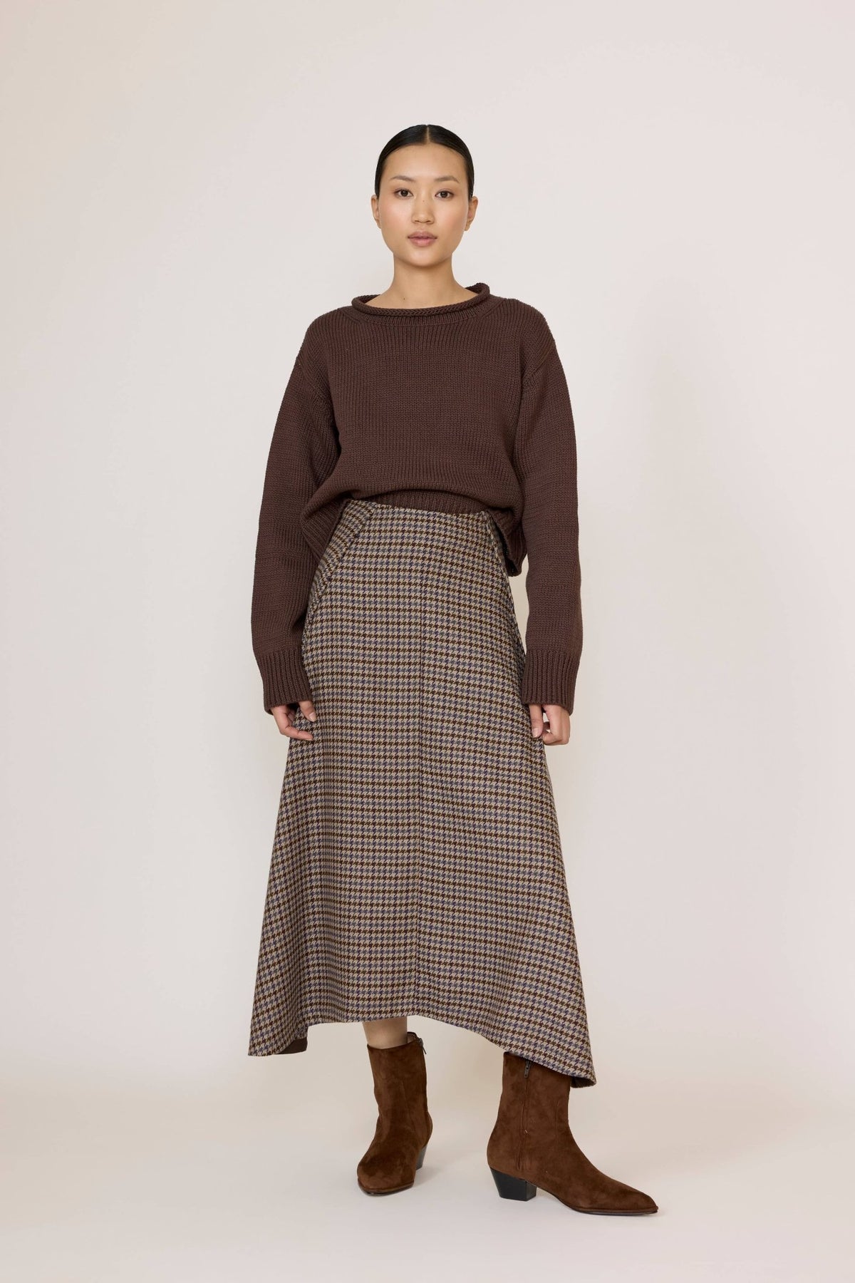 Woman wearing a brown sweater and Laude Flowy Midi Skirt in Wool Plaid on a white background
