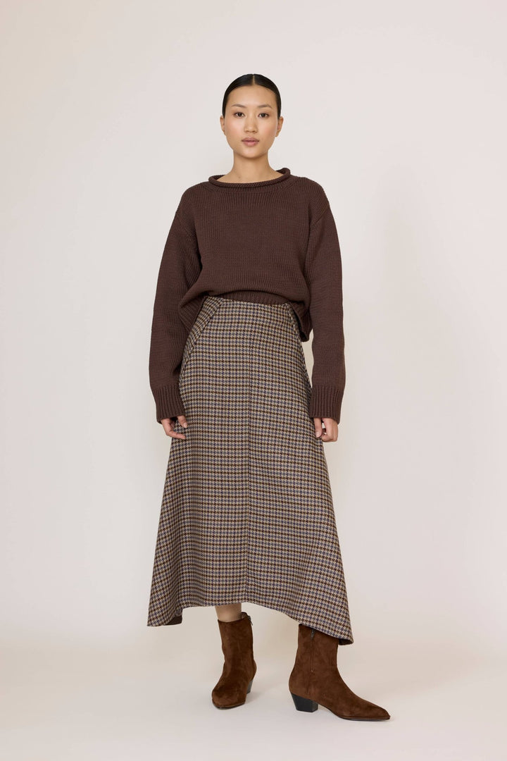 Woman wearing a brown sweater and Laude Flowy Midi Skirt in Wool Plaid on a white background
