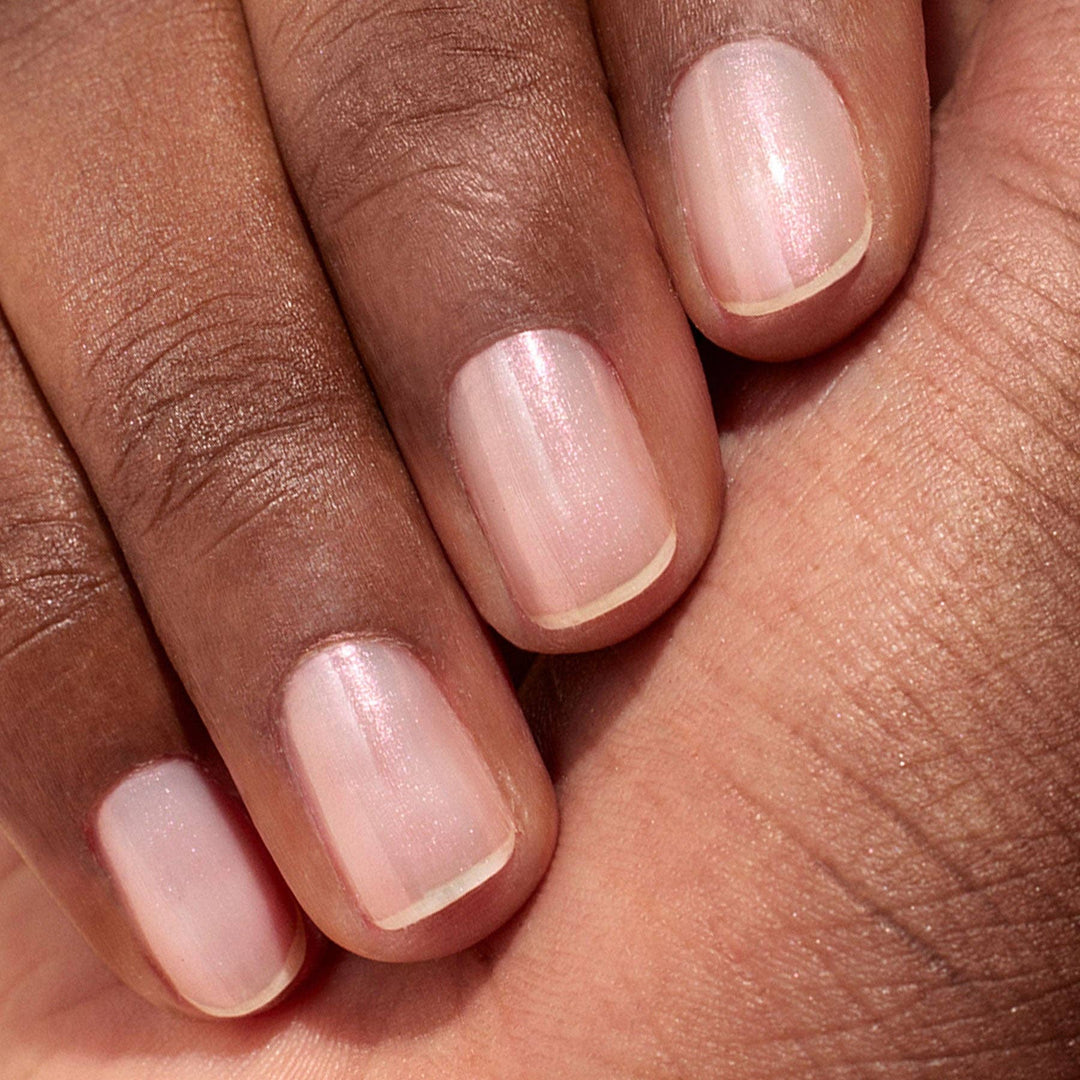 Close-up of a hand with glazed effect powder on nails on a beige background