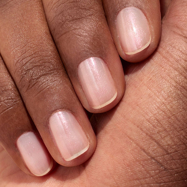 Close-up of a hand with glazed effect powder on nails on a beige background