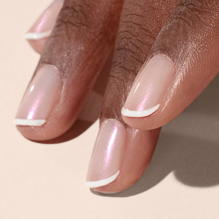 Close-up of a hand with glazed effect powder on nails on a beige background