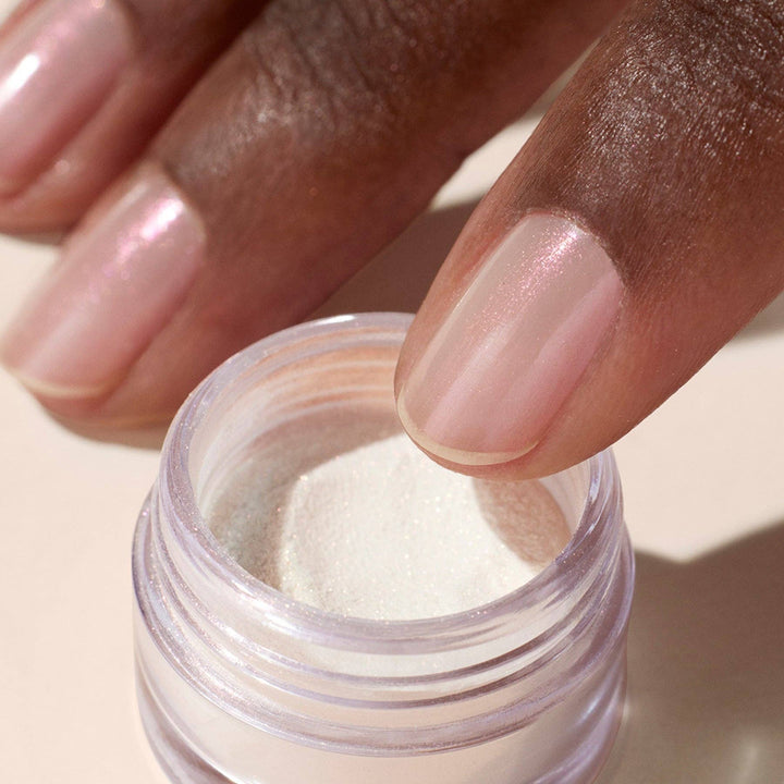 Close-up of a hand with glazed effect powder on nails on a beige background