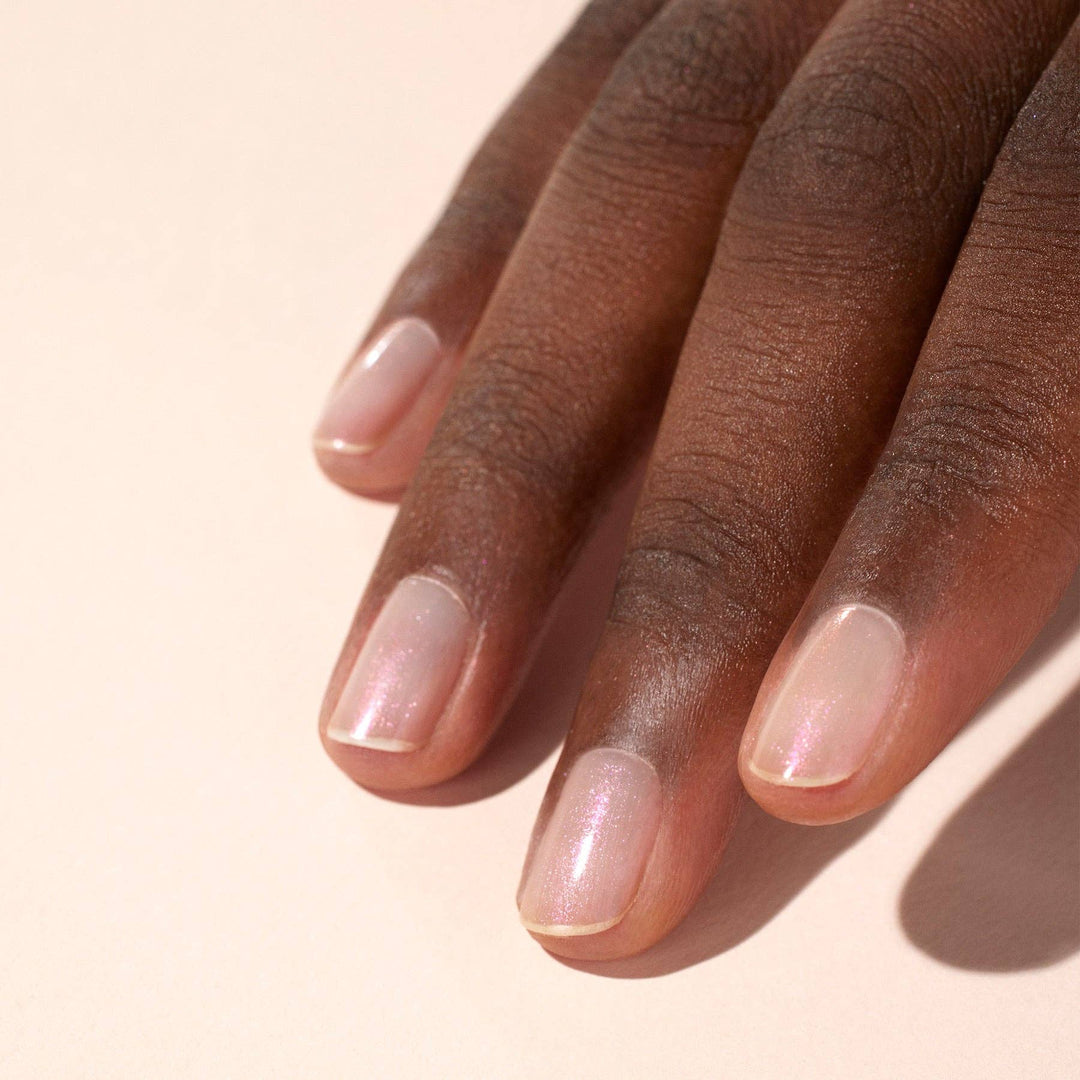 Close-up of a hand with glazed effect powder on nails on a beige background