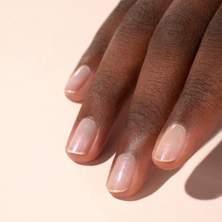 Close-up of a hand with glazed effect powder on nails on a beige background