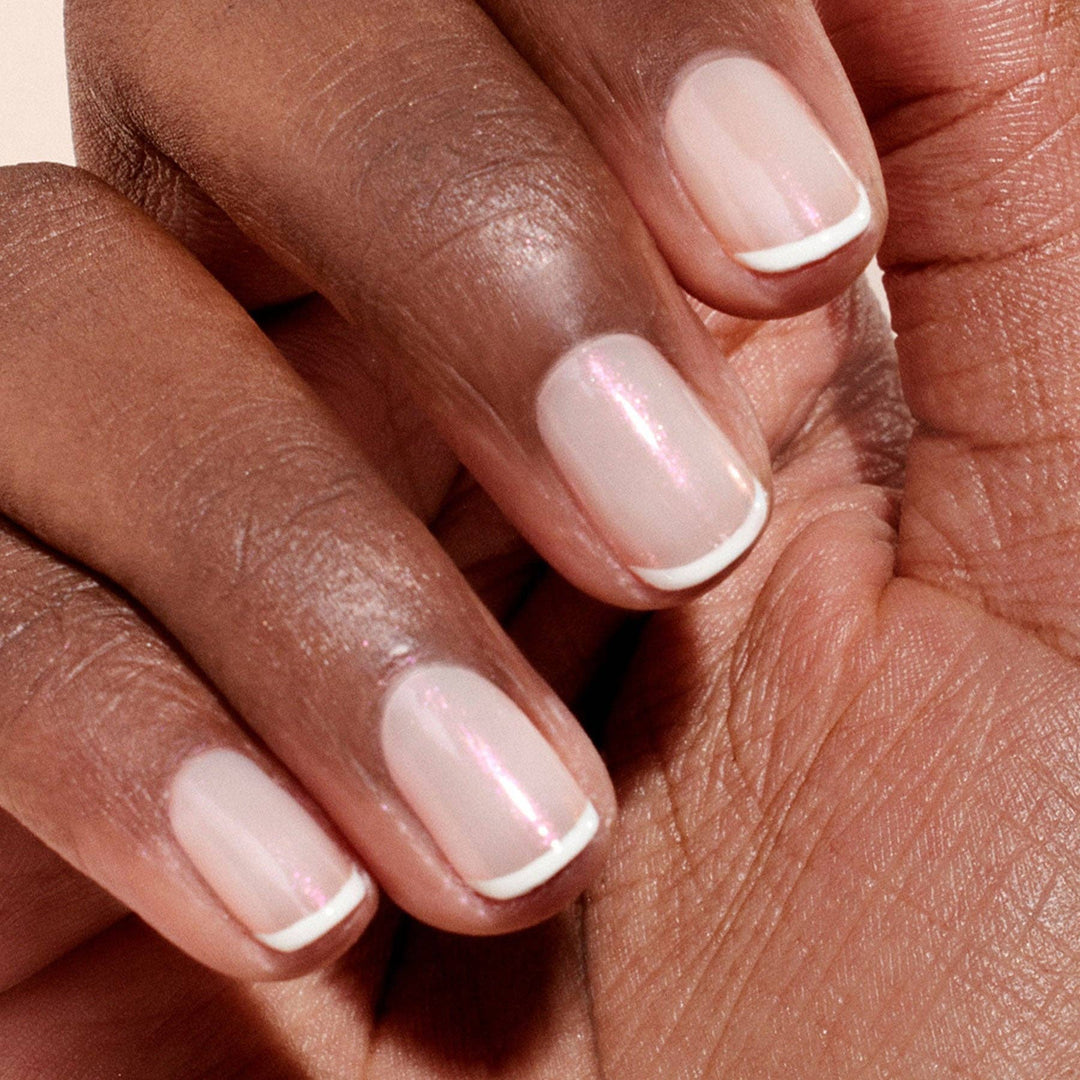 Close-up of a hand with glazed effect powder on nails on a beige background