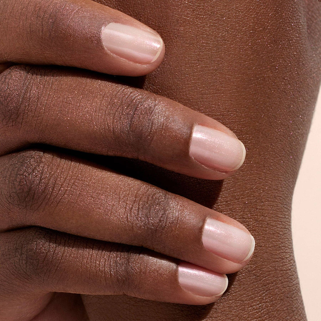 Close-up of a hand with glazed effect powder on nails on a beige background