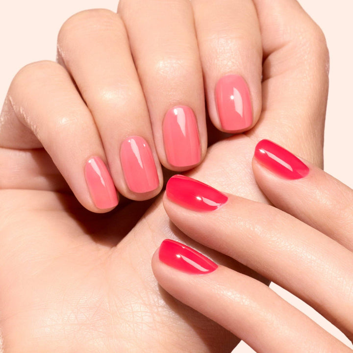Close-up of hands with pink nail polish on a light background