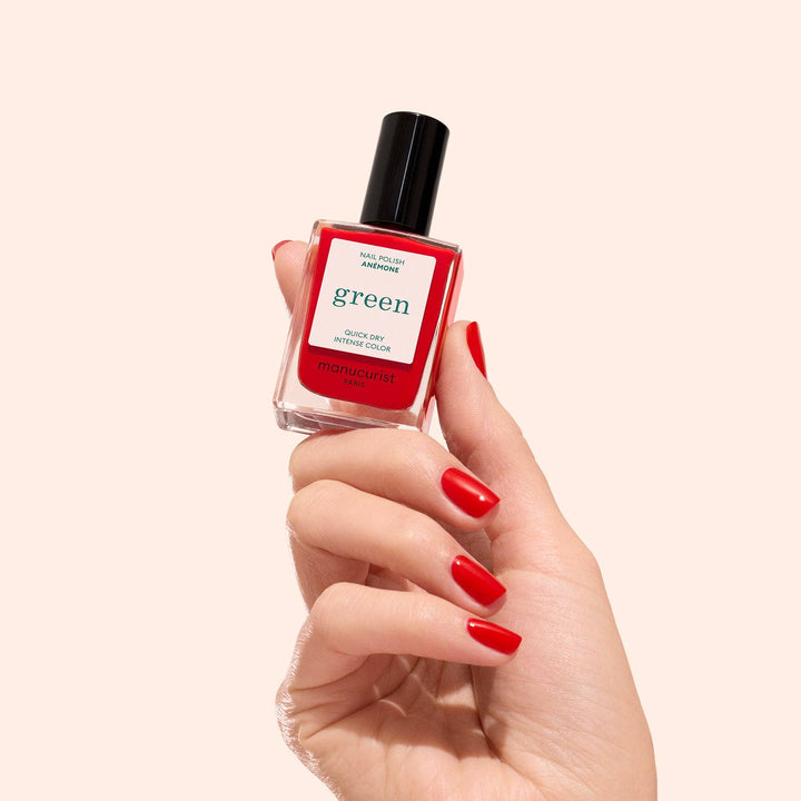 Hand holding a red nail polish bottle labeled &