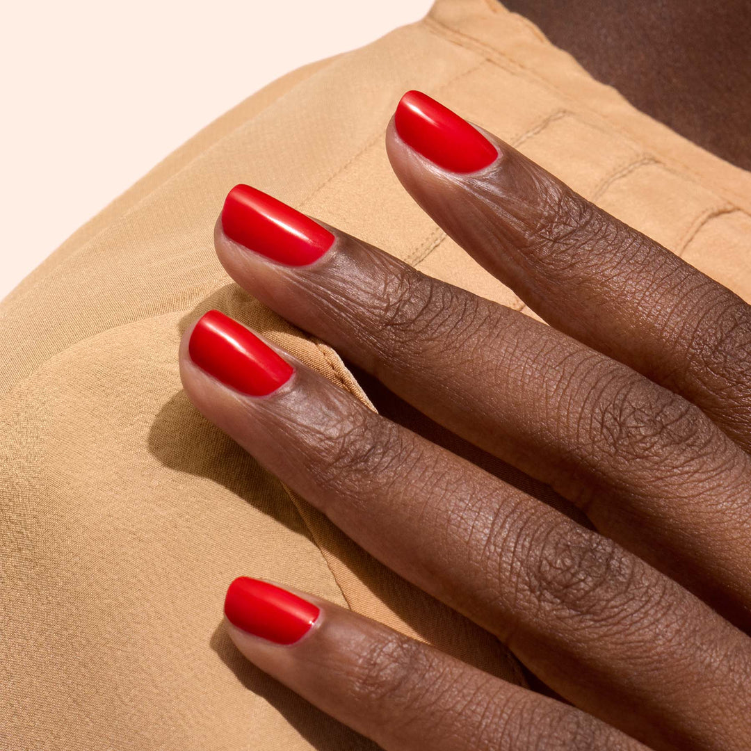 Hand with red nail polish on a beige background