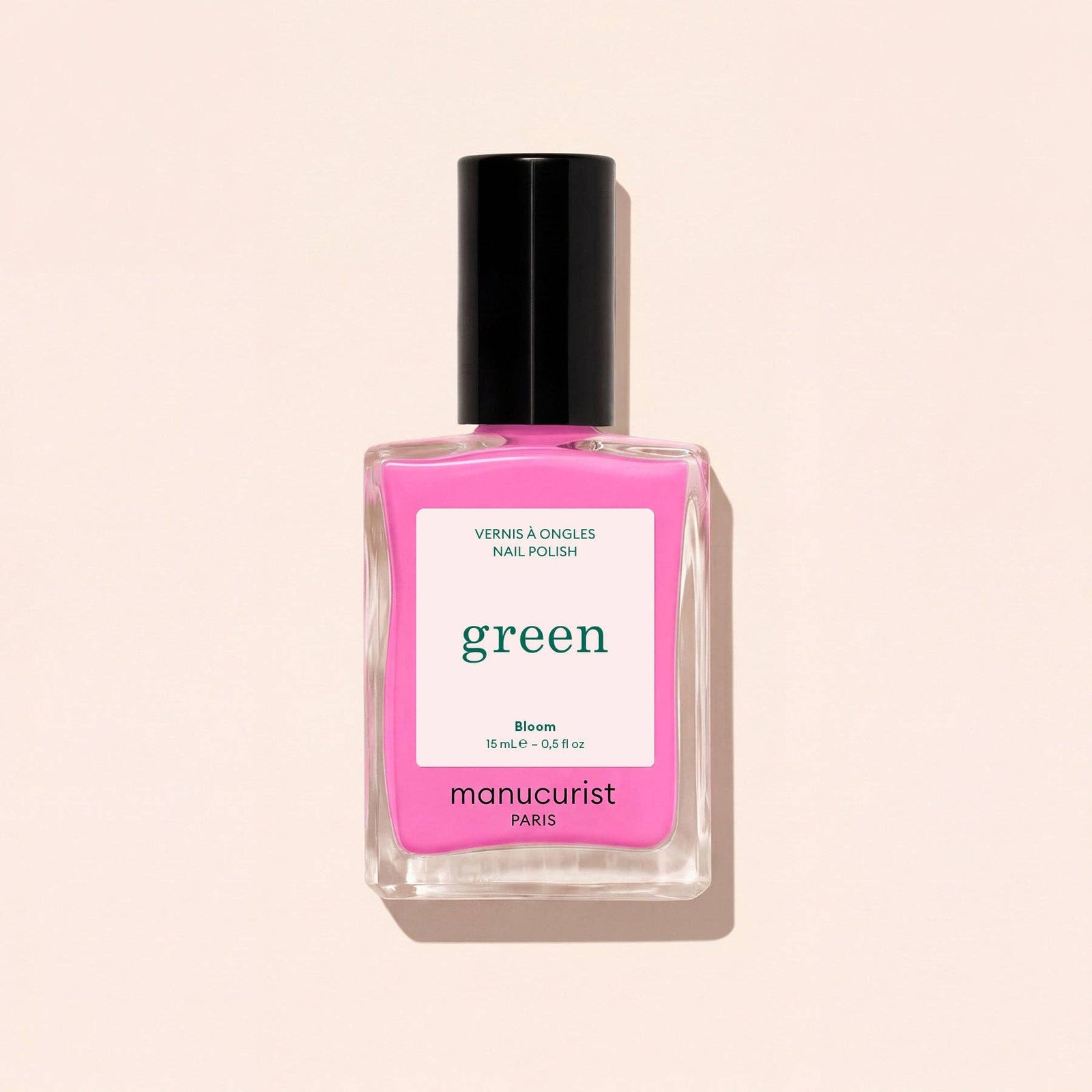 Pink nail polish bottle with 'manucurist' label on a beige background