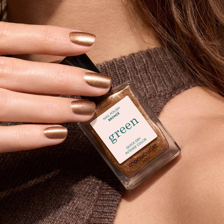 Nail polish with bronze nail polish bottle held by a hand wearing the polish