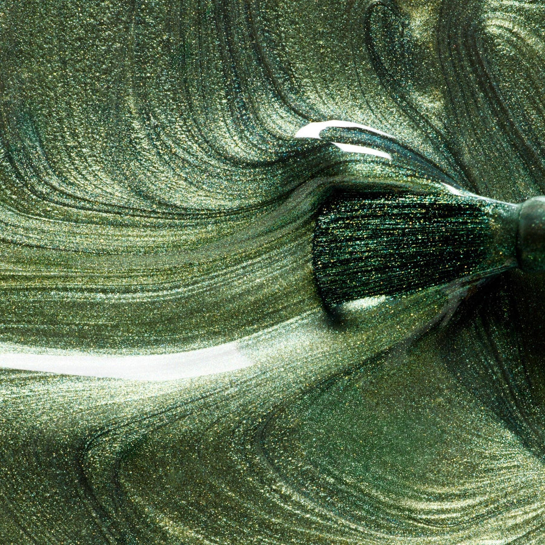 Close-up of a green glittery nail polish with a brush
