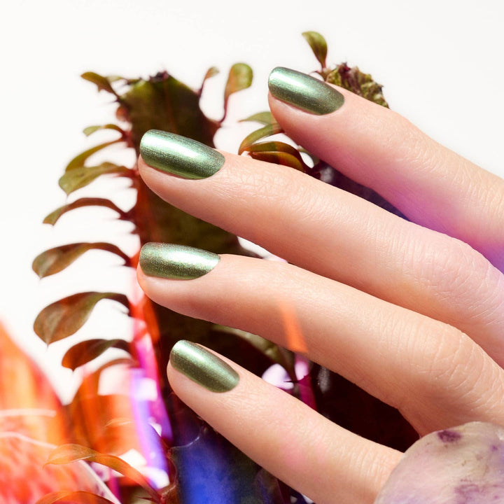 Hand with green metallic nail polish holding a colorful fabric