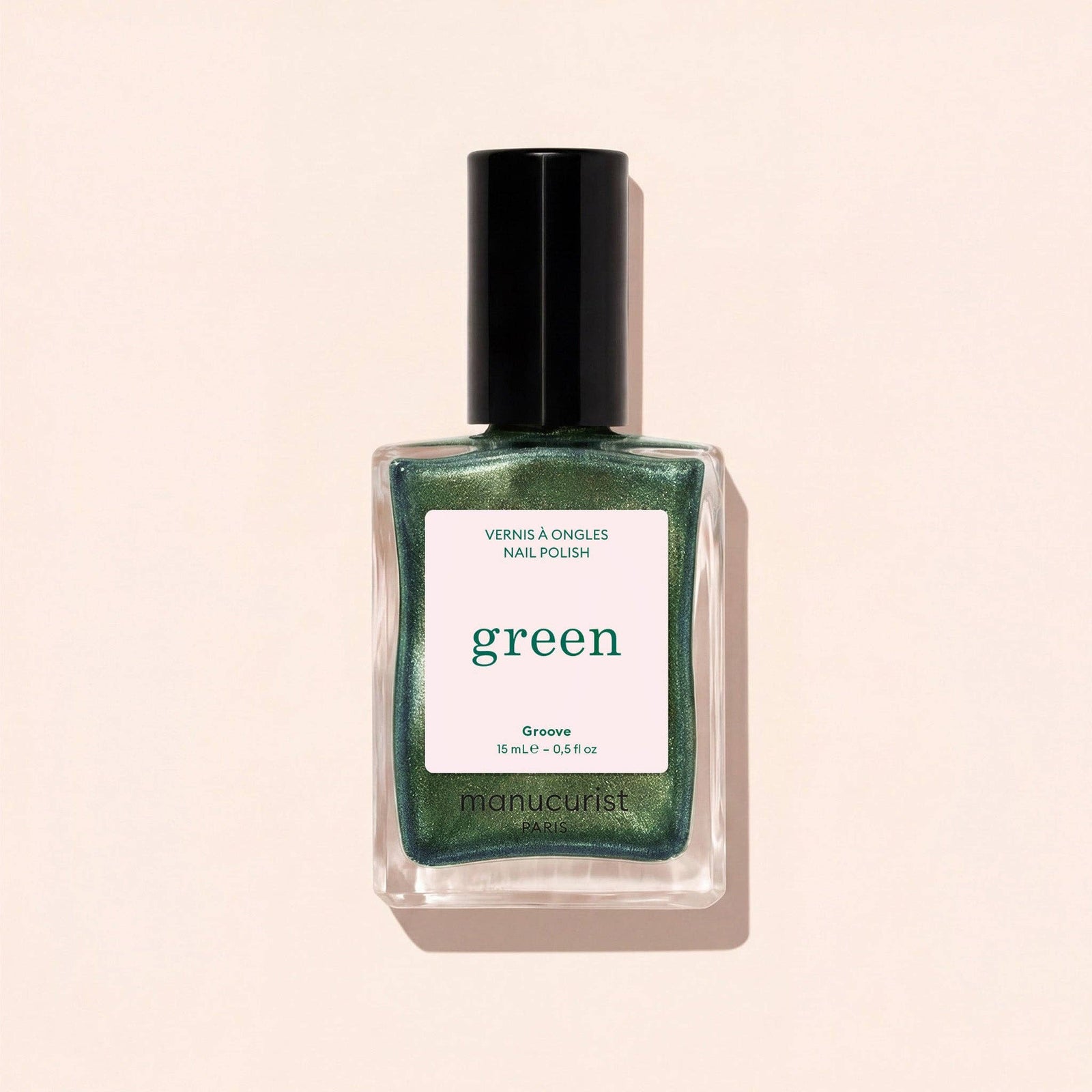 Green nail polish bottle with black cap on a beige background