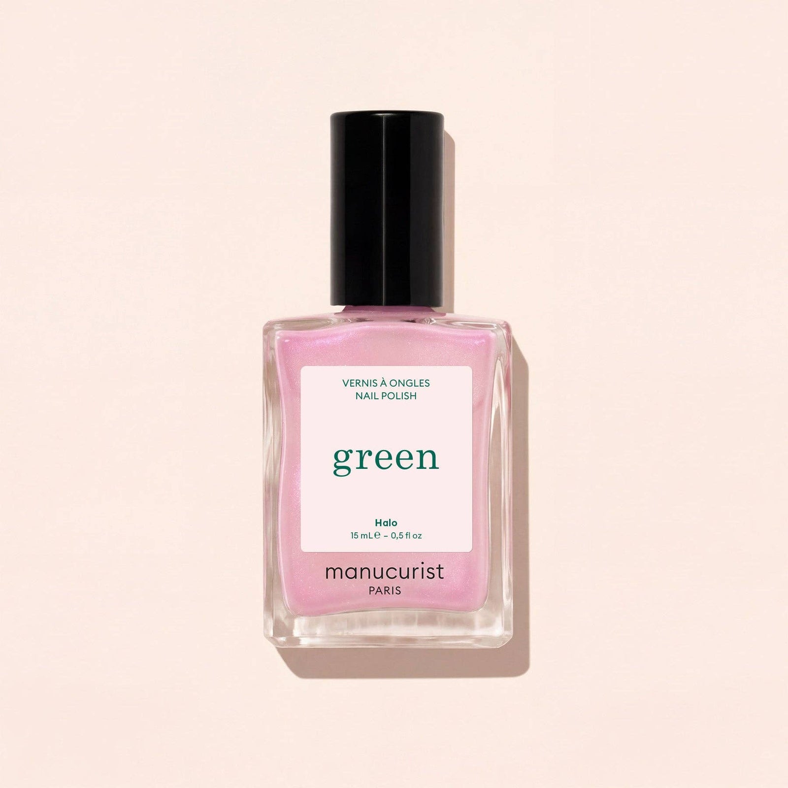 Pink nail polish bottle with 'manucurist' label on a beige background